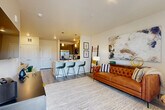 Located in Colorado Springs, CO, this thoughtfully designed 2-bedroom, 1-bathroom residence on Templeton Gap Road makes excellent use of its compact single-floor layout. The open-concept living and kitchen area serves as the heart of the home, seamlessly connecting everyday living and dining spaces. The kitchen is outfitted with gray shaker-style cabinetry, stainless steel appliances including a refrigerator, range, and microwave, a white quartz peninsula with pendant lighting and bar seating for three — ideal for casual dining or entertaining. Wood-look plank flooring runs throughout the main living areas, lending a clean, contemporary feel. The living room is bright and welcoming, featuring large windows and a glass door that opens to a private balcony, filling the space with natural light. A carpeted hallway leads to both bedrooms, each offering plush carpet, natural light from generous windows, and a calm, neutral palette. The primary bedroom provides a comfortable retreat with ample floor area and access to the shared full bathroom. The bathroom features dark cabinetry, a white countertop vanity, wood-look tile flooring, and a glass-enclosed shower. Throughout the residence, clean lines, neutral tones, and modern fixtures create a cohesive and inviting atmosphere.