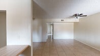 Located at 4848 East Holly Street in Phoenix, Arizona, this two-bedroom residence offers a well-organized single-level layout that makes efficient use of its space. The home features light-toned ceramic tile flooring throughout, neutral walls, and textured ceilings that lend a consistent, cohesive aesthetic across every room.

The living room is a comfortable, open area equipped with a ceiling fan and benefits from natural light filtering in from the adjoining balcony. A sliding glass door with vertical blinds connects the living space to the balcony, providing outdoor access and views of the surrounding area. The dining room flows naturally from the living space, creating a practical and connected common area.

The kitchen is a well-appointed galley-style space lined with rich dark wood cabinetry on both sides, offering generous storage. Light countertops complement the cabinetry, and a window at the far end brings in natural light. White appliances complete the functional setup.

The primary bedroom is a generously sized room with tile flooring and access to a walk-in closet with built-in shelving — a practical organizational feature. The second bedroom offers additional flexibility for use as a guest room or home office. An entrance area welcomes residents into the home, providing a natural transition into the living spaces.