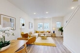 Located in Charlotte, NC, this well-appointed multi-floor home offers a thoughtful layout spread across three levels, combining modern design with functional living spaces. Light wood-tone flooring flows consistently throughout, complementing a bright, neutral color palette that maximizes the sense of openness on every floor.

The entry level features a welcoming hallway with a staircase accented by a large framed mirror, setting an elegant tone from the moment you arrive. The main living floor showcases an open-concept layout where the kitchen and living room share a generous, sun-filled space. The kitchen is outfitted with white shaker cabinetry, stainless steel appliances, a center island with bar seating, and pendant lighting, while the adjacent living area benefits from multiple windows that invite abundant natural light.

The upper floors house two well-proportioned bedrooms, including a primary bedroom with dual windows and a ceiling fan. Two closets provide practical storage, while five clean, modern bathrooms — featuring marble-style tile floors, vanities, and tub/shower combinations — serve the home's residents with ease. A dedicated office with a large window and ceiling fan offers an ideal work-from-home setup. Staircases connect each level seamlessly, making this home as functional as it is visually appealing.