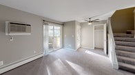 This two-story townhouse offers three bedrooms and one and a half bathrooms across a well-organized floor plan. The kitchen is a functional centerpiece, featuring cream cabinetry, a bold mosaic tile backsplash, dark countertops, and a full suite of stainless steel appliances including a dishwasher, microwave, and refrigerator. Light wood-style flooring runs throughout the main level, lending warmth and continuity to the space.

The bedrooms are carpeted for comfort and each includes a ceiling fan. Natural light filters in through well-placed windows offering views of the surrounding greenery. The primary bedroom features sliding glass doors that open directly onto a private deck overlooking a lush, tree-lined courtyard shared with the community. A closet provides additional built-in storage.

The full bathroom is clean and classic, with white subway tile surrounding a tub-shower combination and dark cabinetry for storage. The half bathroom features white tile flooring, a dark vanity with a marble-style countertop, and a coordinating mirror and wall cabinet.

The covered entry porch and upper-level deck both offer relaxing outdoor spaces with picturesque views of mature trees and well-maintained green lawns. Baseboard heating is present throughout, ensuring year-round comfort in this inviting townhouse.