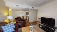 Located at 1901 N Wilmot Rd in Tucson, Arizona, this single-story unit offers a practical and well-arranged floor plan designed for comfortable everyday living. The living room serves as the central gathering space, finished with neutral carpet and a textured ceiling. A large sliding glass door with vertical blinds allows natural light to fill the room and provides outdoor access. The space flows seamlessly into a defined dining area, which features warm hardwood-style flooring, a classic oval wood dining table with Windsor-style chairs, and wall art that adds a touch of character.

The galley-style kitchen is efficiently laid out with dark-countered surfaces, wood-toned cabinetry extending to the ceiling, a double-basin sink, electric range, refrigerator, and dishwasher — providing ample storage and functionality. Hardwood-style flooring continues throughout the kitchen and dining areas.

The bedrooms offer carpeted floors, textured ceilings, and neutral walls, creating a calm and restful atmosphere. Each room provides adequate space for furnishings. Two bathrooms serve the unit, each featuring a shower/tub combination, wood-toned vanity cabinetry, and hardwood-style flooring, delivering a cohesive and practical design throughout the home.