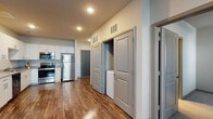 This single-floor residence in Douglasville, Georgia offers a thoughtfully designed open-concept layout that maximizes both functionality and comfort. Rich wood-style flooring flows throughout the main living areas, creating a warm and cohesive aesthetic.

The kitchen is a standout feature, equipped with a full suite of stainless steel appliances including a refrigerator, electric range, microwave, and dishwasher. Crisp white cabinetry extends to the ceiling for ample storage, complemented by granite-style countertops and a double-basin sink — delivering a clean, modern look.

The open living area is generously proportioned, bathed in natural light and fitted with recessed lighting overhead. A dedicated hallway leads to the bedroom spaces, which feature plush carpeting, ceiling fans, and window blinds for privacy and light control. The bedrooms offer comfortable proportions suited for a variety of furniture arrangements.

The bathroom is well-appointed with a vanity, full-size soaking tub, and a bright, functional layout. A spacious walk-in closet with built-in wire shelving provides excellent storage capacity. Additionally, an in-unit laundry closet adds everyday convenience. The space combines practical design with modern finishes throughout.