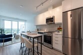 Located at 211 Queen St in Newmarket, Ontario, this one-bedroom, one-bathroom unit offers a thoughtfully designed open-concept layout with modern finishes throughout. Light oak-toned laminate flooring runs seamlessly across the entire space, complemented by bright white walls that enhance the sense of openness.

The kitchen is sleek and well-appointed, featuring flat-panel white cabinetry extending to the ceiling, a marble-look quartz countertop, a subway tile backsplash in a soft grey tone, and a full suite of stainless steel appliances including a refrigerator, electric range, built-in microwave, and dishwasher. A compact island with bar seating provides a practical dining and workspace.

The living area benefits from floor-to-ceiling sliding glass doors that open to a balcony, flooding the space with natural light and offering open views of the surrounding Newmarket skyline and treetops.

The bedroom is a calm and functional retreat, featuring a large sliding-door closet and its own floor-to-ceiling window with balcony access and outdoor views. The bathroom is finished with full-height grey rectangular wall tiles surrounding a soaker tub and shower combination, paired with clean white fixtures and chrome hardware.