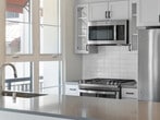 Located at 1650 S Delaware St in San Mateo, CA, Unit 200 at Azara is a thoughtfully designed single-floor residence that blends contemporary finishes with a bright, welcoming atmosphere. The open-concept layout is anchored by a well-appointed kitchen featuring white shaker cabinetry with glass-front upper panels, a stainless steel appliance suite including a gas range and refrigerator, subway tile backsplash, and a large peninsula with a gray quartz-style countertop — ideal for both meal preparation and casual dining. A wide window above the sink frames an outdoor view, flooding the kitchen with natural light. The living area is generously proportioned, with warm-toned luxury vinyl plank flooring, crisp white walls, and access to a private outdoor area through a glass-paneled door. Multiple windows ensure abundant daylight throughout. A dedicated bedroom provides a quieter retreat, finished with soft neutral carpet, a ceiling fan, and a window that continues the home's bright, airy character. The bathroom is clean and simply appointed with a white vanity, matching fixtures, and light wood-look flooring. Throughout the residence, a consistent palette of warm whites and light natural tones creates a cohesive, modern aesthetic well-suited for comfortable everyday living in the heart of San Mateo.
