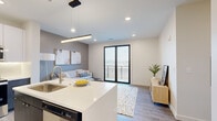 Located at 4201 S Navajo St in Englewood, Colorado, this single-floor residence showcases a contemporary design with clean lines, neutral tones, and high-quality finishes. The open-concept layout seamlessly connects the kitchen and living area, creating a bright and functional shared space anchored by recessed lighting and wood-look flooring.

The kitchen is a standout feature, equipped with stainless steel appliances, two-tone cabinetry combining dark wood-grain lower cabinets with high-gloss white uppers, under-cabinet lighting, and a generously sized island with a white quartz countertop and built-in seating for casual dining.

The living area flows directly to a private balcony through floor-to-ceiling sliding glass doors with black frames, offering sweeping views of the surrounding Englewood landscape. The bedroom features plush carpet, large windows with outdoor views, and access to a well-organized walk-in closet. The bathroom is finished with large-format tile flooring, a glass-enclosed tub and shower combination, and a navy wood-grain vanity topped with a white quartz surface. Throughout the residence, a cohesive palette of warm neutrals and modern accents creates a polished, inviting ambiance.