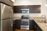 Located on Belfast Drive in Goleta, California, this single-floor residence offers a clean, contemporary design with thoughtfully selected finishes throughout. The open-concept kitchen serves as the centerpiece of the living area, featuring rich dark espresso cabinetry, granite countertops, a peninsula with an undermount sink, and stainless steel appliances including a gas range, microwave, and refrigerator. Pendant lighting above the peninsula adds a polished touch, while recessed ceiling lights illuminate the space evenly. Hardwood-style flooring extends through the kitchen and living areas, lending warmth and continuity to the layout. The living space opens to a private balcony through sliding glass doors, with a ceiling fan overhead enhancing comfort and airflow. The bedrooms are finished with plush wall-to-wall carpeting, crisp white walls, and large windows that invite natural light. Ceiling fans are present in the bedrooms as well, contributing to a comfortable and well-ventilated environment. The overall ambiance is bright, clean, and move-in ready, with a neutral palette that provides a versatile backdrop. Situated in the desirable Goleta area near Santa Barbara, this residence combines functional design with modern finishes in a well-connected location.