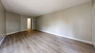 Located at 850 N Benson Ave in Upland, California, this two-bedroom, one-bathroom single-story unit offers a practical and well-organized layout with clean, updated finishes throughout. Light-toned luxury vinyl plank flooring runs continuously across the entire floor plan, complementing neutral warm-gray walls and crisp white baseboards in every room.

The combined kitchen and living area forms the heart of the unit. The kitchen features white cabinetry, dark countertops, a stainless steel refrigerator, a gas range, and an over-the-range microwave, with a peninsula that separates the cooking space from the living area. The living room is generously proportioned, with a sliding glass door that fills the space with natural light and provides access to an outdoor patio area. A wall-mounted HVAC unit and a ceiling fan add to the room's functionality.

Both bedrooms are well-sized with textured ceilings, neutral walls, and ample natural light. The primary bedroom is notably spacious, offering a comfortable retreat. A hallway connects the bedrooms to the full bathroom, which includes a tiled tub-shower combination and white fixtures. Throughout the unit, the consistent use of light tones and updated materials creates a clean, move-in-ready atmosphere.