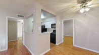 This single-story, 3-bedroom, 2-bathroom home offers a practical and comfortable layout across a compact but efficiently designed floor plan. The living room serves as the heart of the home, highlighted by a striking white-painted brick fireplace that extends floor to ceiling, creating a bold focal point. Warm hardwood-style flooring flows throughout, complemented by neutral-toned walls and abundant natural light streaming through large windows fitted with blinds.

The kitchen is configured as a galley-style space, featuring white cabinetry, light granite-look countertops, and black appliances including a refrigerator, range, and microwave. A pass-through opening connects the kitchen to the adjacent living and dining area, enhancing the sense of openness.

Each of the three bedrooms is equipped with a ceiling fan, hardwood-style flooring, and closet access, offering a consistent, clean aesthetic. The primary bedroom provides a comfortable amount of space with a dedicated closet. A hallway connects the bedrooms and provides access to the two full bathrooms, each featuring a tub-shower combination with white subway tile surround, a white vanity with light countertop, and wood-look flooring. Three additional closets throughout the home provide ample storage. The overall ambiance is clean, neutral, and move-in ready.