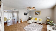 This two-floor home offers a functional and comfortable layout with a variety of well-appointed spaces throughout. The living room serves as a central gathering area, featuring plush carpet, a textured ceiling, a ceiling fan, and a distinctive vertical shiplap accent wall that adds a subtle architectural detail. A wall-mounted television and a gold-framed mirror contribute to the room's practical yet inviting character.

The kitchen is efficiently designed with white cabinetry, light granite-style countertops, a mosaic tile backsplash, a double-basin stainless steel sink, and standard appliances including a dishwasher and electric range. Wood-look flooring runs through the kitchen and connects to the adjacent dining area, which features a sliding glass door that introduces natural light and provides outdoor access.

The bedrooms are carpeted and each includes a ceiling fan. One bedroom benefits from a large window with blinds, allowing ample natural light to fill the space. The bathroom is clean and straightforward, featuring a tub-shower combination, wood-look flooring, and light countertops. Throughout the home, neutral tones create a cohesive and understated aesthetic across both floors.