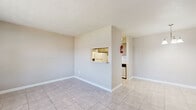 Located at 10555 Spice Ln in Houston, TX, this single-story, one-bedroom, one-bathroom residence offers a practical and well-organized layout. The main living area features neutral-toned walls and light ceramic tile flooring, creating a clean, understated aesthetic throughout the common spaces. A pass-through window connects the living and dining area to the kitchen, promoting an open, communicative feel between rooms. The kitchen is equipped with standard appliances, including a refrigerator and range, complemented by upper cabinetry, a stainless steel sink, and laminate countertops. An adjacent pantry provides additional storage convenience. The bedroom is carpeted for comfort and features a window that brings in natural light and outdoor views. Three closets, including a generously sized walk-in closet with built-in shelving, offer ample storage throughout the unit. The full bathroom includes a single-sink vanity with a light countertop, a large wall mirror, and a tub/shower combination. Consistent tile flooring runs through the main living areas, while carpet adds warmth to the bedroom. The space is efficiently designed to maximize functionality across every room, making it a well-rounded residential unit in the Houston area.