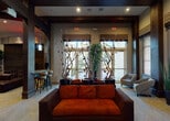 Located at 11338 SW 45th Pl in Miramar, Florida, this single-story community clubhouse offers a thoughtfully designed and versatile gathering space. The interior is defined by bold architectural elements, including dark exposed wood beams, richly stained column frames, and a warm neutral color palette accented with vibrant pops of orange and gold throughout.

The welcoming lounge area features plush burnt-orange seating, tall decorative branch arrangements, and large windows fitted with bamboo-style shades that allow natural light to filter in. Adjacent seating alcoves with patterned accent chairs provide quieter nooks for relaxation, while frosted glass-paneled doors lead to additional rooms beyond.

The game room is a standout feature, equipped with a full-length shuffleboard table, a foosball table, wall-mounted flat-screen televisions, and eclectic décor including a sculptural wall accent. Swivel lounge chairs and upholstered ottomans complete the casual, social atmosphere.

A dedicated bar and café area anchors the entertainment zone, featuring bar-height seating, open shelving, a refrigerator, and multiple large displays mounted above a curved architectural soffit. A communal high-top table surrounded by industrial-style stools provides additional gathering space nearby. Throughout, recessed lighting, textured wallcoverings, and curated décor create an upscale yet inviting ambiance ideal for socializing and recreation.