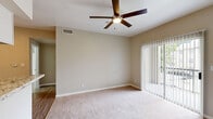 This thoughtfully arranged 2-bedroom, 1-bathroom unit delivers a functional and comfortable single-floor layout. The living room serves as the central gathering space, featuring plush carpeting, neutral beige walls, a ceiling fan with integrated lighting, and a sliding glass door fitted with vertical blinds that opens to an outdoor view, filling the room with natural light.

The galley-style kitchen is a standout feature, showcasing granite-look countertops, white cabinetry with modern hardware, light hardwood-style flooring, track lighting, and stainless steel appliances including a range and refrigerator — offering a clean, contemporary aesthetic.

The primary bedroom is a well-proportioned retreat with soft carpeting, neutral tones, and a ceiling fan. A dedicated walk-in closet equipped with wire shelving and built-in organizers provides ample storage. The second bedroom is equally comfortable, with carpeted floors, neutral walls, and a window with blinds for natural light.

The bathroom includes a full tub-shower combination with white tile surround and chrome fixtures. Additional practicality is provided by a utility room and hallway that connect the spaces efficiently. Throughout the unit, a consistent neutral color palette and clean finishes create a cohesive, move-in-ready atmosphere.