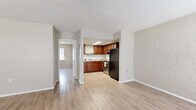 Located at 3809 W Iowa Ave in Tampa, Florida, this single-story home offers a practical and functional layout with a clean, neutral aesthetic throughout. Light wood-style flooring flows consistently across the living areas and bedrooms, creating a cohesive and easy-to-maintain interior.

The living area welcomes natural light through multiple windows fitted with blinds, and features a textured accent wall alongside a wall-mounted air conditioning unit. An adjacent entryway area provides a defined front entrance with its own window, adding to the brightness of the space.

The kitchen is well-appointed with warm, rich-toned wood cabinetry, a classic white subway tile backsplash, light stone-look countertops, and a stainless steel electric range. A black refrigerator and a flush-mounted skylight ceiling fixture round out the functional and attractive kitchen design.

The bedrooms are generously proportioned with neutral-toned walls, textured ceilings, and ample natural light from windows. One bedroom includes a sliding door closet, while another connects directly to the hallway for easy access. The bathroom features large-format warm-toned tile surrounding a full tub-shower combination, complemented by wood-look flooring. Overall, the home presents a tidy, move-in ready environment suited for comfortable everyday living.