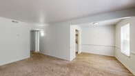 Located at 372 Beechmont Dr in Newport News, Virginia, this two-bedroom, one-bathroom single-floor home offers a clean, neutral interior designed for practical, everyday living. The layout flows from a welcoming living room, finished with plush carpet and bright white walls, into a separate dining area with wood-look flooring that connects directly to the kitchen. The kitchen is equipped with white cabinetry, granite-look countertops, and a stainless steel electric range, offering an efficient and tidy cooking space. Natural light filters throughout the home via multiple windows fitted with blinds. Both bedrooms feature soft carpeting, ample wall space, and natural window views of the surrounding greenery — each room also benefits from dedicated closet storage, with four closets total across the home. The bathroom is well-appointed with white tile surrounding a full tub/shower combo, wood-look flooring, a white vanity, and a large mirror. A hallway connects the private areas of the home to the main living spaces, maintaining a clear and organized flow. The consistent light gray and white color palette throughout lends a clean, move-in-ready feel to the entire space.