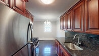 Located at Fairfield-The Pines on West Main Street in Riverhead, NY, this single-floor residence combines classic design with functional living spaces throughout. Crown molding and recessed lighting are consistent finishing touches found across the home, lending a cohesive and polished aesthetic.

The galley-style kitchen is a standout feature, appointed with rich cherry wood cabinetry, dark granite countertops with a matching backsplash, and gleaming high-gloss tile flooring. Stainless steel appliances — including a gas range, refrigerator, and microwave — complete the space, which opens toward a dining area illuminated by a classic chandelier and a bright window.

The living areas are generously proportioned, featuring plush wall-to-wall carpeting, ceiling fans with light fixtures, and windows that bring in natural light. Crown molding frames each room with a traditional, elegant touch.

The primary bedroom is notably spacious, offering multiple closets for ample storage, ceiling fan, and recessed lighting. Additional bedrooms are well-sized and similarly finished with carpeting and ceiling fans. A hallway with recessed lighting and carpeted flooring connects the rooms seamlessly.

The bathroom features a tiled tub-and-shower combination enclosed by sliding glass doors, with a granite-topped vanity adding a refined detail consistent with the rest of the home.