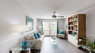 Located at 2100 S Conway Rd in Orlando, Florida, this single-floor, 2-bedroom, 3-bathroom home offers a well-organized layout with a comfortable and cohesive design throughout. The living room features wood-look flooring, a ceiling fan, and large sliding glass doors that allow abundant natural light and outdoor views, creating an open and airy atmosphere. Adjacent to the living area, the dining room includes wood-look flooring, a round glass-top table area, wainscoting details, and a pass-through to the kitchen, which is finished in white cabinetry. The spacious primary bedroom is appointed with plush carpet, a ceiling fan, and a window with outdoor views, complemented by an en-suite bathroom featuring a white vanity with a granite-style countertop and mirrored medicine cabinet. The second bedroom also features carpet flooring, a ceiling fan, and a wide window that brings in natural light. The three bathrooms are clean and functional, with one featuring a full soaking tub and separate toilet area with light wood-look flooring. A hallway connects the bedrooms and shared spaces efficiently. The overall design palette of neutral grays, whites, and wood tones creates a bright, welcoming ambiance throughout the home.