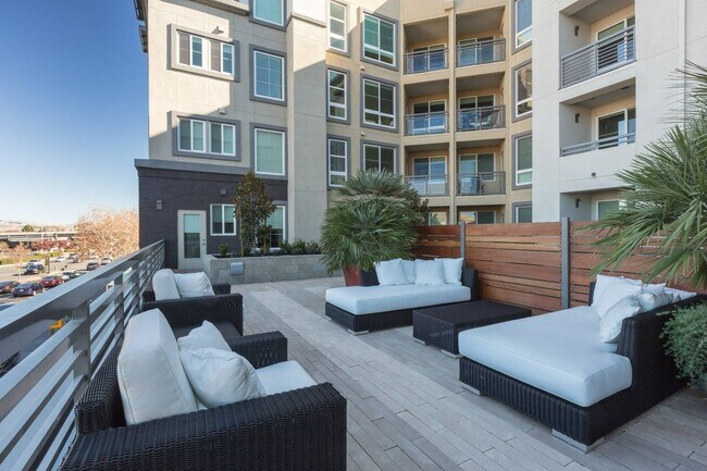 Área de estar al aire libre con muebles modernos y chimenea en Aster Apartments en Dublin, CA. - Aster