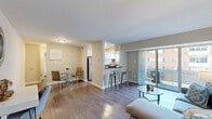 Located at 402 Westover Hills Blvd in Richmond, Virginia, this one-bedroom, one-bathroom residence offers a well-organized single-floor layout within a classic brick multi-story building surrounded by lush greenery. The open-concept living and dining area is anchored by rich hardwood-style flooring, neutral walls, and a large sliding glass door that floods the space with natural light and opens onto a private balcony overlooking a landscaped courtyard. The kitchen is thoughtfully equipped with white shaker-style cabinetry, dark granite countertops, stainless steel appliances including a gas range and refrigerator, and a window above the sink providing additional natural light. A dedicated dining nook adjacent to the kitchen provides a functional space for everyday meals. The generously sized bedroom features plush carpeting, large double closets offering ample storage, and a bright window dressed with sheer curtains. The full bathroom includes a clean white tub-shower combination with wood-style flooring, maintaining a bright and functional aesthetic throughout. In-unit laundry is accessible directly from the bedroom, adding a layer of everyday convenience. The private balcony overlooks a well-maintained green lawn framed by mature trees, offering a peaceful outdoor retreat.