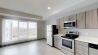 Located at 20 Cherokee Blvd in Chattanooga's desirable North Shore area, this single-floor unit offers a clean, contemporary design with an efficient and open layout. Light-toned luxury vinyl plank flooring runs throughout the main living areas, contributing to a bright and cohesive aesthetic.

The kitchen is a standout feature, outfitted with a full suite of stainless steel appliances including a refrigerator, electric range, over-the-range microwave, and dishwasher. Light wood-grain cabinetry extends both above and below the counters, providing generous storage, while white countertops offer a crisp contrast. The kitchen flows naturally into the living area, creating an open and functional living space.

The living area benefits from a large window dressed with vertical blinds, allowing abundant natural light and offering views of the surrounding cityscape and green space. Recessed lighting overhead complements the natural illumination throughout.

The unit also includes a bathroom with clean, white finishes, and interior doors with a modern charcoal finish that add a subtle design accent. The overall color palette — whites, light grays, and warm wood tones — creates a calm, contemporary ambiance well-suited to comfortable everyday living in the heart of Chattanooga.