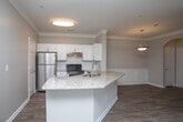 Located at 601 DeKalb Industrial Way in Decatur, Georgia, this single-floor residence offers a well-designed open-concept layout that seamlessly connects the kitchen, dining, and living areas. The kitchen is a standout feature, equipped with stainless steel appliances including a refrigerator, range, and dishwasher, complemented by crisp white shaker-style cabinetry, a subway tile backsplash, and granite countertops. A center island with a sink adds both functionality and visual appeal, while a pendant light overhead enhances the space. Crown molding throughout the main living areas adds a refined architectural touch. The living room is anchored by a classic white fireplace and benefits from natural light streaming through large windows. Hardwood-style flooring runs throughout the main living spaces, while the bedrooms feature plush carpeting for added comfort. Each bedroom is appointed with ceiling fans and windows that allow natural light to fill the rooms. The bathroom includes a granite-topped vanity with white cabinetry, a tub-shower combination, and wood-style flooring, offering a clean and functional finish. Neutral wall tones throughout create a calm, versatile ambiance well-suited for a variety of interior styles.