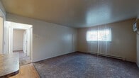 Located at 751 Miner Dr in Medina, Ohio, this single-floor unit offers a straightforward, functional layout designed for comfortable everyday living. The spacious living area is finished with plush carpeting and neutral-toned walls, creating a clean, versatile backdrop. A window dressed with sheer curtains allows natural light to filter in, while a baseboard heating unit and wall-mounted air conditioner provide year-round climate control. The living area transitions openly into the kitchen, which is a standout feature of the space. Rich, dark wood cabinetry extends to the ceiling, offering generous storage, and is complemented by granite-style countertops, a subway tile backsplash, and light hardwood flooring. White appliances, including a refrigerator, range, and dishwasher, complete the functional cooking space. A peninsula counter connects the kitchen to the living area. The bedrooms are carpeted and well-sized, each featuring windows with blinds that bring in natural light and baseboard heating. One bedroom is notably equipped with dual bi-fold closets offering ample storage with built-in shelving and hanging rods. The bathroom includes a full tub-shower combination, a wood-toned vanity with a white countertop, and tile flooring, maintaining a clean and practical aesthetic throughout.