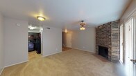 This two-story home in Houston's Ashford Point neighborhood offers a functional and comfortable layout across two levels. The main floor features a spacious living area with neutral-toned carpet, a ceiling fan, and a standout brick fireplace that anchors the room with classic character. French doors along one wall flood the space with natural light and provide access to the exterior. Adjacent to the living area, the kitchen is appointed with dark espresso cabinetry, granite-style countertops, a matching dark tile backsplash, tile flooring, and black appliances including a range and dishwasher. A full bathroom on this level features a dark granite vanity and a tiled shower-tub combination. Upstairs, the bedrooms are carpeted and well-proportioned, each with ceiling fans and blinds-covered windows that allow for natural light. One bedroom features vaulted ceilings, adding a sense of openness and volume to the space. A second full bathroom upstairs mirrors the dark vanity aesthetic seen throughout the home. The consistent use of dark cabinetry and granite-style finishes in the wet areas ties the design together, while the neutral walls and plush carpeting throughout create a warm, cohesive living environment.