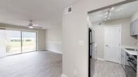 Located at 5724 Riverdale Road in College Park, GA, this one-bedroom, one-bathroom unit offers a comfortable and efficiently designed single-floor layout. The living room is a welcoming, open space finished with light-toned luxury vinyl plank flooring and neutral beige walls accented by white chair-rail molding. A ceiling fan with integrated lighting keeps the room comfortable, while a sliding glass door floods the area with natural light and provides direct views of the surrounding greenery outdoors. The bedroom is a generously sized retreat, also featuring LVP flooring, a ceiling fan, and a bright window with white blinds that allow for natural light control. A dedicated closet provides ample storage. The kitchen is outfitted with gray shaker-style cabinetry, light countertops, and a stainless steel sink, offering a clean and modern aesthetic. The bathroom includes a full tub-shower combination with white subway tile surround and chrome fixtures, maintaining a crisp, clean look throughout. A connecting hallway ties the layout together seamlessly. Textured ceilings are present throughout the unit, adding a classic residential character. The overall ambiance is bright, neutral, and move-in ready.