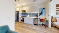 Located at 1530 Cassil Place in the heart of Hollywood, this thoughtfully designed one-bedroom, one-bathroom unit on the fourth floor offers a well-appointed living experience with a clean, contemporary aesthetic throughout. Light hardwood flooring flows seamlessly across the open-concept layout, connecting the kitchen, living area, and bedroom with a cohesive, modern feel.

The kitchen is efficiently designed with white cabinetry extending to the ceiling for ample storage, a striking blue subway tile backsplash, and a full suite of stainless steel appliances including a gas range, microwave, dishwasher, and refrigerator. A dedicated workspace is integrated directly into the kitchen area, offering a functional spot for remote work.

The bedroom is a bright and serene retreat, benefiting from natural light that pours in through full-height sliding glass doors that open directly onto a private balcony. The outdoor space provides elevated views of the surrounding Hollywood neighborhood, including tree-lined streets and hillside scenery. Built-in wardrobe cabinetry provides clean, generous storage.

The bathroom is a design highlight, featuring bold cobalt blue brick-pattern tiles in the glass-enclosed shower, contrasted by a crisp white geometric-patterned floor and minimalist floating vanity — a striking combination of color and texture that elevates the overall space.