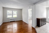 This 2-bedroom, 1-bathroom unit at 939E Western in London, Ontario offers a well-organized layout across a single floor. Warm hardwood flooring runs throughout the living areas and bedrooms, complemented by neutral white walls and textured ceilings that create a clean, consistent aesthetic.

The living area benefits from a large window overlooking greenery outside, allowing generous natural light to fill the space. A radiator heating unit provides reliable warmth. The layout flows from the entry hallway into the living space, with clear sightlines connecting to the kitchen and bedrooms.

The kitchen features tile flooring, stainless steel appliances including a stove and refrigerator, a tiled backsplash in earthy tones, warm-toned cabinetry, and a bright window with outdoor views of trees and lawn.

The primary bedroom is a comfortable size, featuring two windows that flood the room with natural light and views of the surrounding landscape. The second bedroom also includes hardwood floors, a window, and a radiator. Both rooms maintain the neutral, light toned palette seen throughout the unit.

The bathroom includes tile flooring, white cabinetry for storage, and a bathtub with tiled surround. The space is practical and efficiently laid out, with grab bars installed for added accessibility.