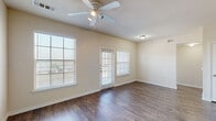This single-story 2-bedroom, 1-bathroom home offers a practical and comfortable layout designed for everyday living. The combined kitchen and living room forms the heart of the home, featuring rich dark hardwood-style flooring, neutral warm-toned walls, and ceiling fans throughout. Multiple windows fitted with white horizontal blinds flood the space with natural light, while a private exterior door provides convenient outdoor access directly from the living area.

The kitchen is well-equipped with warm wood cabinetry, laminate countertops, a peninsula with a double sink, and black appliances including a refrigerator, range, and microwave. An adjacent pantry provides additional storage for kitchen essentials.

Both bedrooms are finished with plush carpet and ceiling fans, each offering natural light through large windows. The primary bedroom is generously sized and includes a dedicated walk-in closet with wire shelving. In total, four closets are distributed throughout the home, ensuring ample storage options.

The full bathroom features a dual-sink vanity with a wide mirror, hardwood-style flooring, and a clean, functional layout. A dedicated laundry room adds further convenience to this thoughtfully arranged home. A connected hallway ties all rooms together for a cohesive and efficient flow throughout the space.