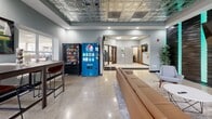 Located on Cass Avenue in Detroit's Midtown neighborhood, The Union is a thoughtfully designed single-floor community and amenity space that blends urban character with functional comfort. The entrance hallway sets the tone immediately, featuring polished terrazzo flooring, a wall-mounted TV, package lockers, and a striking large-scale mural celebrating Detroit's culture and identity, rendered in vivid, colorful detail alongside bold street signage art.

The main lounge area is a standout centerpiece, boasting an ornate embossed tin ceiling that adds architectural elegance overhead. A textured black accent wall with teal LED lighting strips frames a sleek electric fireplace, creating a modern yet inviting atmosphere. Comfortable seating, including a caramel leather sofa and contemporary armchairs, is arranged around a round coffee table, making the space ideal for relaxing or socializing.

Adjacent to the lounge, the breakroom continues the tin ceiling aesthetic and offers a full counter with cabinetry, small appliances, and a high-top dining table with bar-height chairs. Vending machines provide added convenience nearby.

A private office off the hallway features natural light from window blinds, a wood-toned desk, ergonomic seating, and colorful wall art, creating a productive yet comfortable workspace. The overall ambiance throughout is polished, community-focused, and distinctly Detroit in spirit.