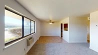 This single-floor residence offers a well-organized layout that balances comfort and functionality across its key living spaces. The main living area is a highlight of the unit, featuring a combination of tile and carpet flooring, a ceiling fan with light fixture, and a wide bank of windows that invite generous natural light and outdoor views. A wall-mounted HVAC unit ensures year-round climate control, and the textured ceiling adds a classic touch to the space.

The kitchen is thoughtfully appointed with rich, dark cherry-toned cabinetry offering ample storage, granite-look countertops, a double stainless steel sink, and a stainless steel range. A decorative stone tile backsplash adds visual warmth and character to the cooking area.

The unit includes two bedrooms, both finished with plush carpet flooring and textured ceilings. Each room benefits from natural light through well-placed windows, and one bedroom features a double-door closet providing convenient storage. Clean white walls throughout create a neutral, move-in ready canvas.

The bathroom is clean and efficiently designed, featuring a full tub-shower combination with built-in shelving, a toilet, a vanity with dark cabinetry, and tile flooring. A secondary toilet area with chrome hardware completes the bathroom offerings. Overall, the space presents a tidy and functional residential layout.