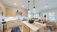This single-floor residence offers a thoughtfully designed open-concept layout that maximizes functionality across its two bedrooms and two bathrooms. Light wood-tone flooring runs throughout, creating a cohesive and airy aesthetic from entry to living spaces.

The kitchen is a standout feature, outfitted with flat-front light wood cabinetry, white subway tile backsplash, white quartz countertops, and a full suite of stainless steel appliances. A central island with pendant lighting provides additional prep space and casual seating, while open shelving adds display versatility. The kitchen flows directly into the living area, which benefits from multiple windows allowing generous natural light and a ceiling fan overhead.

Both bedrooms are comfortably sized, each featuring neutral tones and dedicated closet space. The primary bedroom offers a quiet, well-proportioned retreat. The two bathrooms are finished in crisp white tile with matte black hardware accents, one featuring a tub-shower combination.

A dedicated laundry room houses a full-size washer and dryer. The hallway includes a built-in shelving closet for additional storage. Overall, the space presents a clean, modern aesthetic with a warm and livable ambiance.