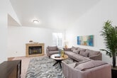 This single-floor residence offers a thoughtfully designed layout that balances comfort and functionality across its key living areas. The living room serves as a welcoming centerpiece, featuring soaring vaulted ceilings, soft carpet underfoot, and a tile-surround fireplace that anchors the space. Natural light filters in through windows dressed with blinds, and the open sightlines create a generous sense of scale. A dedicated entry corridor transitions seamlessly into the main living areas, with hardwood flooring extending through the dining area and kitchen. The dining room is highlighted by an elegant chandelier and a sliding glass door that fills the space with additional natural light. Adjacent to the dining area, the kitchen is outfitted with white cabinetry, granite-style countertops, a breakfast bar with seating, and a full suite of appliances. Two well-proportioned bedrooms each feature plush carpeting, large windows with outdoor views, and ample wall space. The full bathroom includes a tub-shower combination, hardwood flooring, and granite-topped vanity cabinetry. Throughout the residence, a consistent palette of crisp whites and warm neutrals lends a cohesive, clean aesthetic.