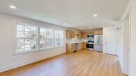 Located at 701 Bowling Ave in Nashville's 37215 zip code, this 2-bedroom, 1-bathroom unit offers a clean, modern aesthetic throughout. The open-concept kitchen and living area serves as the heart of the home, featuring light hardwood flooring, recessed lighting, and a large bank of windows that flood the space with natural light and offer views of the surrounding neighborhood. The kitchen is well-appointed with light maple cabinetry, a tile backsplash, white countertops, and a full suite of stainless steel appliances including a French door refrigerator, range, microwave, and dishwasher. Both bedrooms are bright and efficiently designed, with light hardwood floors, crisp white walls, and wall-mounted mini-split units for individualized climate control. The bathroom is finished to a high standard, featuring a marble-topped vanity, tile flooring, and a glass-enclosed walk-in shower with gold-tone hardware and white subway tile surround. A staircase provides access to the unit, and the overall layout makes practical use of the available space. The unit presents a fresh, move-in-ready condition with a cohesive, light-toned palette throughout.