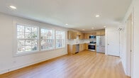Located at 701 Bowling Ave in Nashville's 37215 zip code, this 2-bedroom, 1-bathroom unit offers a clean, modern aesthetic throughout. The open-concept kitchen and living area serves as the heart of the home, featuring light hardwood flooring, recessed lighting, and a large bank of windows that flood the space with natural light and offer views of the surrounding neighborhood. The kitchen is well-appointed with light maple cabinetry, a tile backsplash, white countertops, and a full suite of stainless steel appliances including a French door refrigerator, range, microwave, and dishwasher. Both bedrooms are bright and efficiently designed, with light hardwood floors, crisp white walls, and wall-mounted mini-split units for individualized climate control. The bathroom is finished to a high standard, featuring a marble-topped vanity, tile flooring, and a glass-enclosed walk-in shower with gold-tone hardware and white subway tile surround. A staircase provides access to the unit, and the overall layout makes practical use of the available space. The unit presents a fresh, move-in-ready condition with a cohesive, light-toned palette throughout.