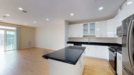 This two-story residence features 2 bedrooms and 2 bathrooms, designed with a clean, contemporary aesthetic throughout. The open-concept main living area seamlessly connects the kitchen and living space, creating an airy and functional environment ideal for both everyday living and entertaining. The kitchen is a standout feature, showcasing high-gloss white cabinetry, dark granite countertops, and a central island that provides additional prep and seating space. Recessed lighting illuminates the space evenly, complementing the warm-toned hardwood flooring that runs throughout the main level. Stainless steel appliances and modern hardware complete the kitchen's polished look. The neutral color palette of soft whites and warm beiges throughout contributes to a bright, welcoming ambiance. The two-floor layout allows for a clear separation between the living and sleeping areas, offering both functionality and privacy. The minimalist design approach ensures that the space feels uncluttered and versatile, providing residents with a comfortable and stylish home that is ready to be personalized.