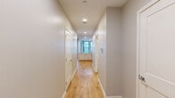 Located at 10 Main St in Fitchburg, MA, this single-floor unit offers three bedrooms, two bathrooms, and a well-designed layout across a comfortable living footprint. Light hardwood flooring flows consistently throughout the space, lending warmth and visual continuity to every room.

The kitchen is a standout feature, equipped with crisp white shaker cabinetry, light stone-finish countertops, and a full suite of black appliances including a refrigerator, electric range, built-in microwave, and dishwasher. Recessed lighting and an open sightline into the hallway enhance the kitchen's functional appeal.

The bedrooms are bright and generously proportioned, with large windows framing views of the surrounding Fitchburg streetscape. The primary bedroom benefits from corner window placement, allowing natural light from multiple directions. Two closets serve the unit, including one fitted with a multi-tier wire shelving system for organized storage.

The two bathrooms offer clean, neutral finishes. One features a walk-in shower with built-in shelving and chrome fixtures, while the second includes a vanity with an integrated sink and a tub area with chrome towel bars. Neutral wall tones throughout the unit create a calm, move-in-ready aesthetic.