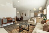 Located at 8810 C Ave in Hesperia, CA, this single-story home offers a well-designed layout with thoughtful finishes throughout. The kitchen is a functional centerpiece, featuring light maple cabinetry with ample upper and lower storage, granite-look countertops, stainless steel appliances including a gas range, over-the-range microwave, and full-size refrigerator, all set atop durable wood-look flooring. A peninsula counter provides a seamless transition into the adjacent living area. The living room impresses with soaring vaulted ceilings and large windows that invite generous natural light, creating an open and airy atmosphere. The dining area continues the vaulted ceiling design and is anchored by a chandelier overhead, adding a touch of elegance to the space. Bedrooms offer plush carpeting, ceiling fans, closet storage, and windows that bring in natural light. The primary bathroom features an extended vanity with a wide mirror and wood-toned cabinetry, while a secondary bathroom provides a similarly clean and functional design. Wood-look flooring flows consistently through the main living areas, tying the home together with a warm, cohesive aesthetic. This home presents a comfortable and practical living environment suited for everyday life.