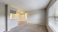 Located on Richmond Ave in Houston, TX, this single-floor unit offers three bedrooms and two bathrooms within a thoughtfully laid-out floor plan. The combined kitchen and living area serves as the heart of the home, where wood-look flooring flows through the kitchen and transitions to plush carpet in the living space. A peninsula with a marble-style countertop and integrated sink separates the two areas, providing both a functional workspace and a casual gathering spot. The galley-style kitchen is well-equipped with gray cabinetry lining both walls, white appliances including a range and refrigerator, and ample counter storage. The living area is open and airy, finished in neutral tones that lend a clean, versatile backdrop. Each of the three bedrooms features soft carpeting, ceiling fans with light fixtures, and windows dressed with blinds that invite natural light. The primary bedroom is generously sized and includes a dedicated closet. The bathrooms are finished with marble-style vanity countertops and wood-look tile flooring, offering a cohesive, updated aesthetic. Clean lines and a neutral palette carry throughout, creating a calm and functional living environment.