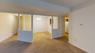 Located at 1150 Kenly Ave in Hagerstown, Maryland, this single-floor apartment offers a practical and comfortable layout with distinct living, dining, and sleeping areas connected by an open, flowing floor plan. The living room is a generous, carpeted space anchored by a fireplace and a sliding glass door that invites natural light and provides access to the outdoors. Adjacent to the living room, the dining area features its own chandelier and is visually connected to the kitchen through pass-through openings, enhancing the sense of openness throughout the space. The U-shaped kitchen is well-equipped with warm oak cabinetry, ample counter space, a double-basin sink, and white appliances including a coil-top range and a full-size refrigerator, all set over easy-care tile flooring. The bedroom is a bright, carpeted retreat with two windows that frame views of the surrounding greenery, allowing for excellent natural light and ventilation. The bathroom continues the warm wood-toned cabinetry theme, featuring a wide vanity with a large mirror, a lighted vanity bar, two windows with outdoor views, and tile flooring. Throughout, the unit maintains a clean, neutral palette that offers a versatile and move-in ready living environment.