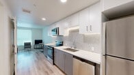 Located at 9530 Reseda Blvd in Northridge, California, this thoughtfully designed studio unit makes efficient use of its single-floor layout. The galley-style kitchen is a standout feature, showcasing two-tone cabinetry with crisp white upper cabinets and sleek gray lower cabinets, complemented by a white quartz countertop and a distinctive hexagonal tile backsplash. Stainless steel appliances — including a range, over-the-range microwave, dishwasher, and refrigerator — provide full functionality within a streamlined footprint. Light wood-look flooring runs throughout the space, creating a warm and cohesive aesthetic. The open living and sleeping area is bright and airy, benefiting from a large window that allows natural light to fill the room. Recessed lighting throughout adds to the clean, modern ambiance. The bathroom continues the contemporary design language, featuring gray cabinetry beneath a white vanity, a large mirror, and matching light wood flooring. A dedicated closet provides practical storage. The unit's efficient, well-planned design makes it a functional and stylish space, ideal for single occupancy in the heart of Northridge.
