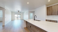 Located at 18220 N 68th St in Phoenix, AZ, this modern 2-bedroom, 2-bathroom residence offers a thoughtfully designed single-floor layout with clean contemporary finishes throughout. Light wood-look flooring flows seamlessly across the open-concept living and kitchen area, creating a cohesive and inviting atmosphere. The kitchen is a standout feature, boasting a large center island with a white quartz countertop, an undermount sink with a matte black faucet, and wood-toned cabinetry that extends to the upper wall. Stainless steel appliances, including a built-in microwave, range, and French door refrigerator, complete the space. The living room is bright and airy, enhanced by a ceiling fan and sliding glass doors that open to a private balcony with exterior views. Both bedrooms feature the same warm wood-look flooring, with the primary bedroom offering direct access to a well-appointed en-suite bathroom. The primary bath includes a wood-finish vanity with a white countertop, an illuminated mirror, matte black hardware, large-format tile accents, and a walk-in closet with built-in shelving and hanging rods. The second bathroom and additional closet provide ample storage and functionality throughout.