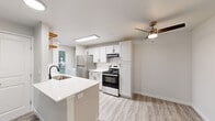 This thoughtfully designed single-floor residence offers 2 bedrooms and 2 bathrooms within a bright, efficiently laid-out floor plan. The open-concept kitchen and living area form the heart of the home, featuring light-toned vinyl plank flooring and a ceiling fan that enhances airflow and comfort. The kitchen is well-equipped with white shaker-style cabinetry, stainless steel appliances including a gas range and refrigerator, quartz countertops, an undermount sink with a matte black faucet, and warm-toned open wood shelving for added character. A peninsula provides additional prep space and casual seating. The living area is bright and open, with a sliding glass door that invites natural light and provides direct outdoor access. Both bedrooms are comfortably sized, with the primary bedroom offering a generously proportioned closet with sliding doors. The secondary bedroom features a large window with greenery views and a baseboard heating unit. The bathrooms are clean and functional, with one featuring a full soaking tub and shower combination, pedestal sink, framed mirror, and brushed nickel fixtures. Neutral tones and modern finishes are carried consistently throughout, creating a cohesive and inviting living environment.