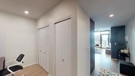 Located in the heart of downtown Phoenix at 200 E Fillmore St, this single-floor residence offers a thoughtfully designed layout with modern finishes throughout. Light hardwood flooring runs continuously across the space, complementing the clean, contemporary aesthetic.

The living area is bright and open, anchored by floor-to-ceiling windows that frame panoramic views of the Phoenix skyline. A ceiling fan adds comfort, while the glass-and-steel design elements lend an urban, sophisticated feel. The space flows naturally toward a private balcony, extending the living area outdoors.

The kitchen is well-appointed with dark wood cabinetry, white quartz countertops, stainless steel appliances including a full-size refrigerator and gas range, and a stainless undermount sink — all designed for both function and style.

The bedroom is a standout, featuring dramatic deep-toned accent walls, a ceiling fan, and expansive floor-to-ceiling windows offering commanding city views. A built-in bench along the window wall provides a comfortable vantage point to take in the urban landscape.

A hallway connects the living spaces to additional storage, including louvered bifold closet doors and a full-panel closet, ensuring ample organization. The overall ambiance of the residence is modern, airy, and urban, ideal for those seeking a connected downtown Phoenix lifestyle.