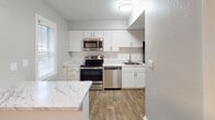 Located at 6060 Reserve Dr. in Charlotte, NC, this single-floor home offers a well-designed layout with a range of thoughtfully appointed spaces. The kitchen is a standout feature, outfitted with crisp white cabinetry, marble-look countertops, a classic subway tile backsplash, and a full suite of stainless steel appliances including a range, microwave, and dishwasher. Wood-look flooring ties the kitchen together with a clean, contemporary aesthetic.

The living area is generously sized, with plush carpeting underfoot and French doors that invite natural light and provide outdoor access. Neutral gray walls create a calm, versatile backdrop throughout the home. The bedrooms are comfortably proportioned, each featuring soft carpeting, neutral-toned walls, and multiple windows with blinds that allow for natural light while maintaining privacy.

The primary suite includes a well-appointed bathroom with a long white vanity, wood-look flooring, and direct access to both a walk-in closet and a separate water closet with a shower. An additional bathroom features a full tub-shower combo with clean white finishes. The overall design is modern and move-in ready, with consistent finishes that lend a cohesive, polished feel throughout the entire space.