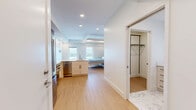 Located at 801 E Whiting St in the heart of Tampa, FL, this thoughtfully designed single-floor unit makes exceptional use of its compact footprint. Light hardwood flooring runs throughout, anchoring a bright, open-concept kitchen and living area bathed in natural light from multiple windows that frame views of the downtown Tampa skyline.

The kitchen is a standout, featuring stainless steel appliances including a full-size range and French door refrigerator, two-tone cabinetry with wood upper panels and white lower cabinets, a light blue mosaic tile backsplash, and a sleek white peninsula with an integrated sink — ideal for both meal prep and casual dining.

The living area showcases clever built-in space-saving design, including a Murphy-style wall bed system with an integrated sofa and a warm wood-paneled ceiling accent overhead, maximizing functionality without sacrificing style.

Two well-appointed bathrooms feature crisp white finishes, with the primary bath offering a glass-enclosed walk-in shower, a vanity, and striking large-format hexagonal marble-look tile flooring. A dedicated utility closet with built-in shelving and in-unit washer/dryer adds everyday convenience. Recessed lighting throughout ensures a clean, modern ambiance across every room.