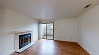 This single-story, 3-bedroom, 2-bathroom home offers a practical and comfortable layout across a compact but efficiently designed floor plan. The living room serves as the central gathering space, featuring warm hardwood-style flooring, a tile-surround fireplace with a classic white mantel, and a sliding glass door that opens to an outdoor patio, filling the room with natural light and providing a seamless indoor-outdoor connection.

The kitchen is accessible via a pass-through window from the main living area, creating an open feel while maintaining defined spaces. It is equipped with warm-toned wood cabinetry, granite-look countertops, black appliances including a refrigerator, range, and over-the-range microwave, and a window that brings in additional natural light.

The three bedrooms are carpeted for comfort, with the primary bedroom offering its own sliding glass door to a private patio area. The two bathrooms are finished with wood vanities, granite-look countertops, and hardwood-style flooring, with at least one bathroom featuring a standalone glass-enclosed shower. Additional spaces include a utility room and a dedicated closet, rounding out the functional layout of this well-organized home.