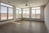 Located at 905 River Rd in Charlottesville, Virginia, this single-floor space offers a clean, contemporary design with a cohesive aesthetic throughout. The open-concept layout seamlessly connects the living area to the kitchen, creating a spacious and functional flow.

The kitchen is a standout feature, outfitted with rich wood-grain cabinetry that extends floor to ceiling, providing generous storage. A crisp white subway tile backsplash contrasts beautifully with the warm cabinetry tones, while light-colored quartz countertops complete the modern look. A full suite of stainless steel appliances — including a refrigerator, range, over-the-range microwave, and dishwasher — ensures the kitchen is well-equipped.

The living area is bright and airy, benefiting from a wraparound arrangement of large windows that flood the space with natural light and offer expansive views of the surrounding landscape. Light wood-style flooring runs continuously throughout, enhancing the sense of openness. A ceiling fan adds both function and a finishing touch to the living space.

The bathroom features matching wood-grain cabinetry with a white countertop vanity and a large mirror, maintaining the consistent modern aesthetic. A well-organized hallway connects the rooms efficiently. Clean white walls and neutral finishes throughout give the space a fresh, move-in-ready feel.