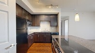 This well-appointed 2-bedroom, 1-bathroom home with a den is located in Broomfield, Colorado, offering a comfortable and functional single-level layout. The open-concept kitchen is a standout feature, showcasing rich dark-brown cabinetry, granite countertops, a tile backsplash, and black stainless appliances including a range and refrigerator. A peninsula with pendant lighting bridges the kitchen to the living area, which is highlighted by a classic fireplace framed in tile and neutral carpeting. Large windows with vertical blinds allow ample natural light to fill the living space, creating a bright and welcoming ambiance. The primary bedroom offers generous proportions, plush carpet, dual windows, and a ceiling fan, while the second bedroom and den provide flexible living options. The walk-in closet includes built-in shelving and dual hanging rods for ample storage. The bathroom is finished with granite countertops, dark wood cabinetry, tile flooring, a framed mirror, and a tub/shower combo with decorative tile accents. Throughout the home, a consistent design palette of dark wood tones, granite, and neutral walls conveys a cohesive and polished aesthetic.